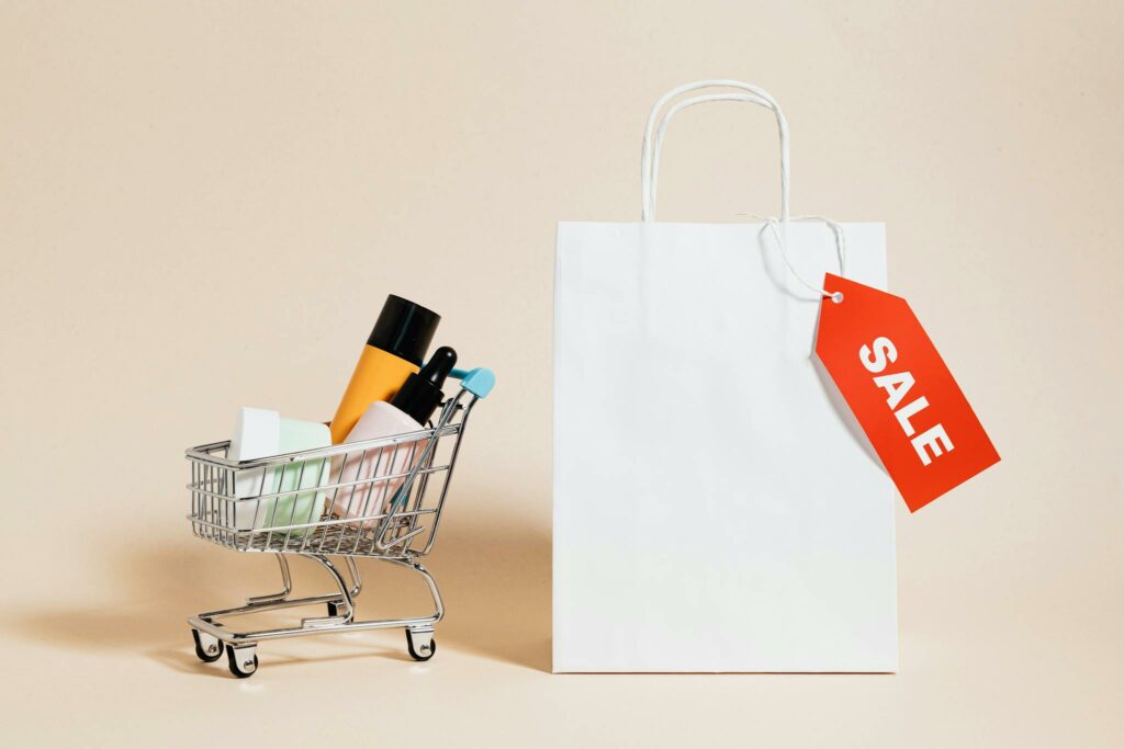 Minimalist image featuring a shopping cart with products and a sale-tagged bag.